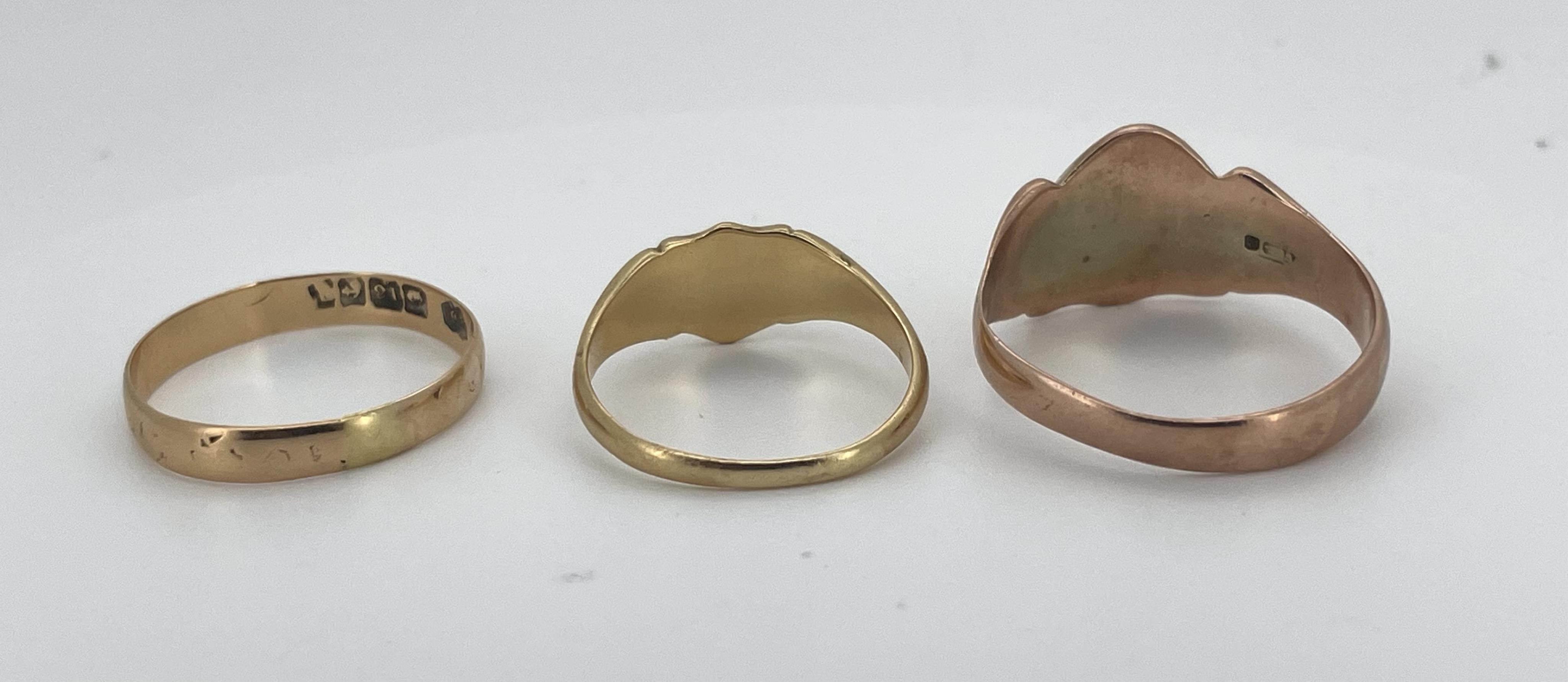 Three gold rings, comprising: a Victorian 18ct gold shield-shaped signet ring, bearing the monogram RMW, to a fluted band, size O, British hallmarks, gross weight approximately 3 grams; an 18ct gold wedding band, size R,